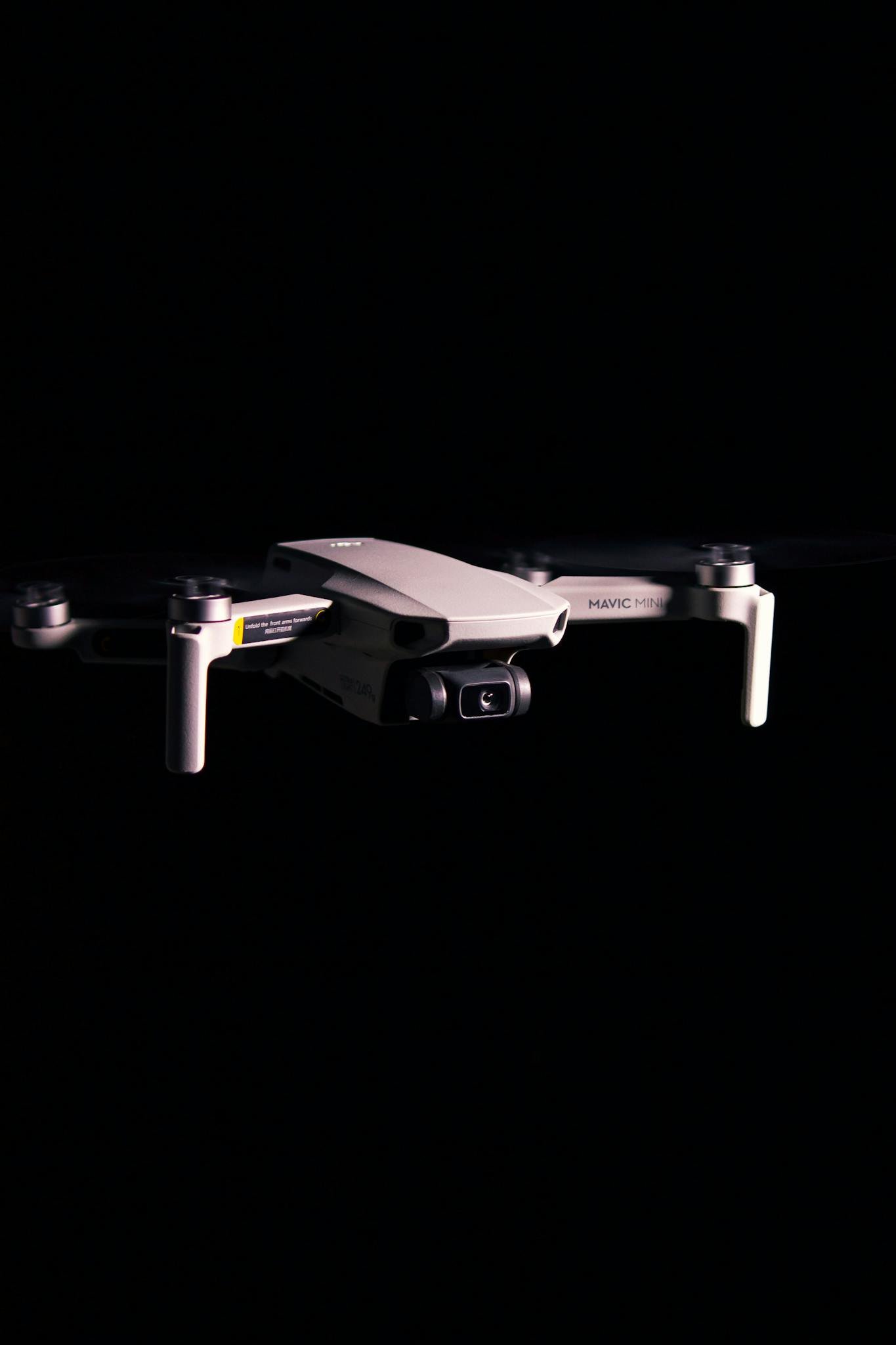 A sleek drone mid-flight against a black background, showcasing cutting-edge technology.